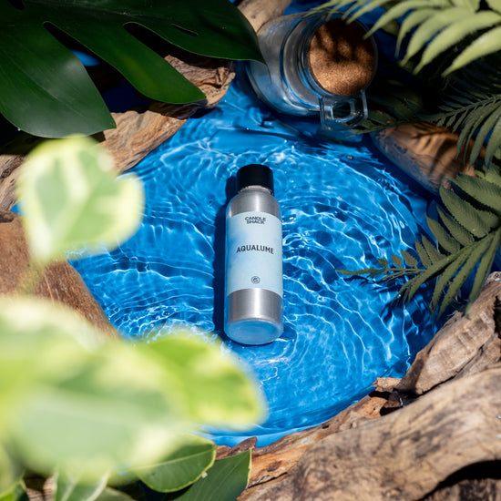 Die Duftflasche "AquaLume" von Candle Shack im Wasser, umgeben von Palmen