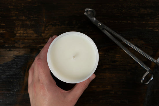 Hand holding a container candle with candle snips next to it