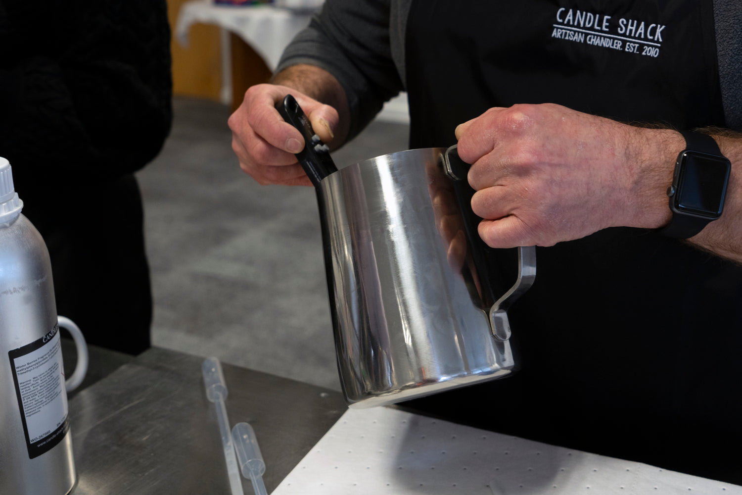Measuring the temperature of wax and fragrance in a stainless steel jug.  Messung der Temperatur von Wachs und Duft in einem Krug aus Edelstahl.