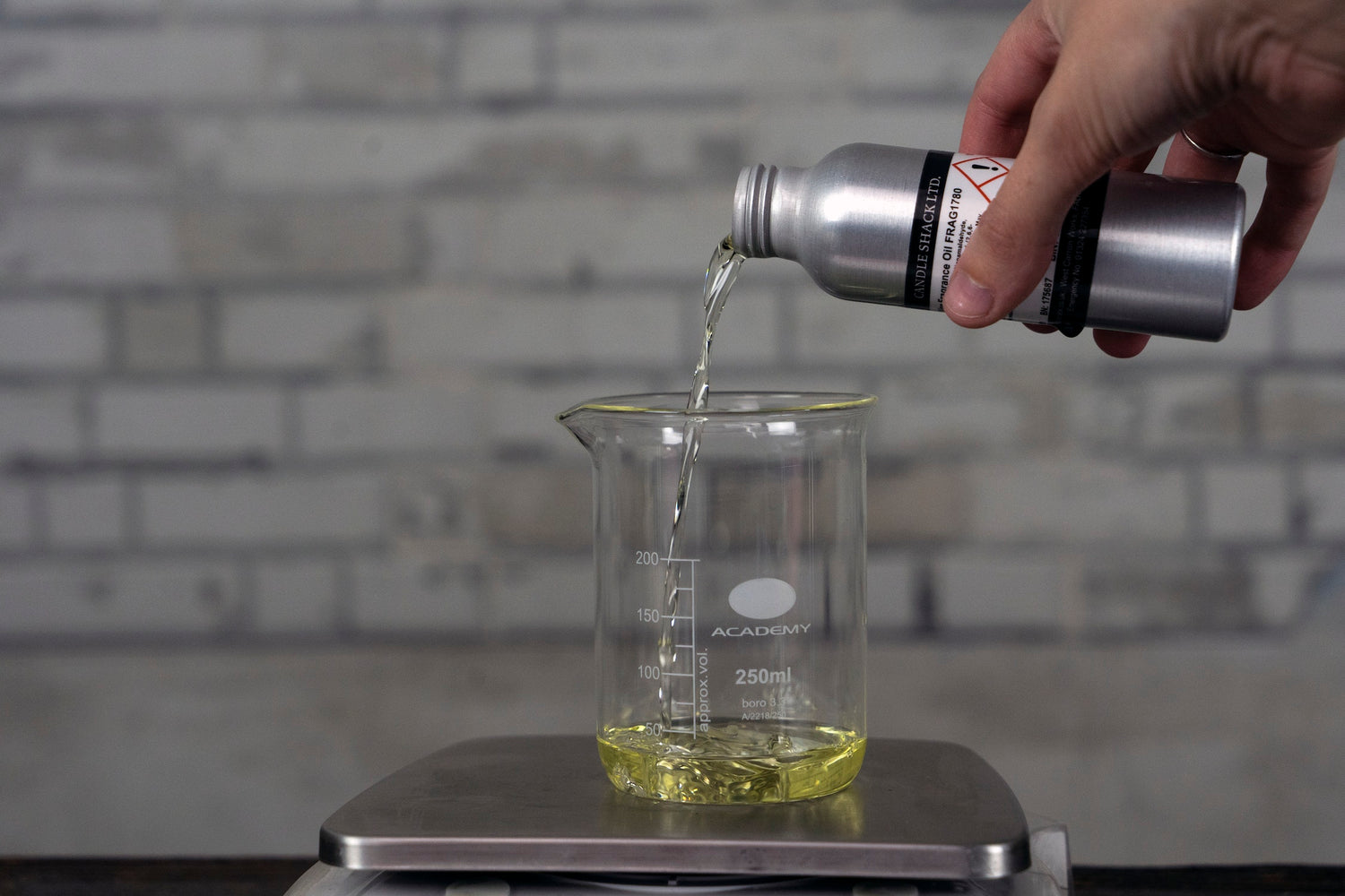 Pouring fragrance oil into a beaker on a set of scales Gieße Duftöl in einen Becher auf einer Waage